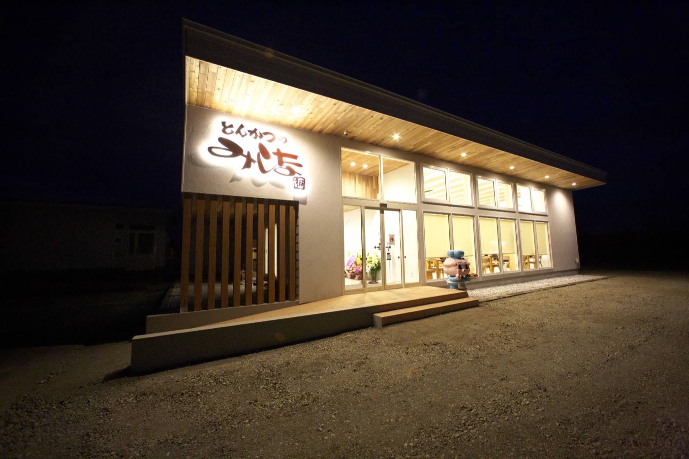 夜の店舗外観。木の格子と暖かい照明